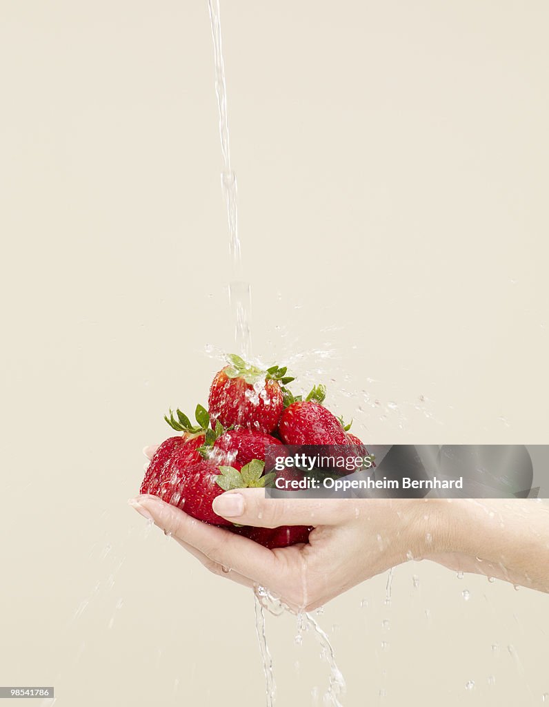 Holding strawberries with water splashing on