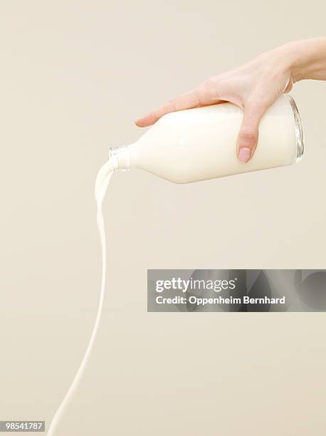 female hand pouring milk from container - botella de leche fotografías e imágenes de stock
