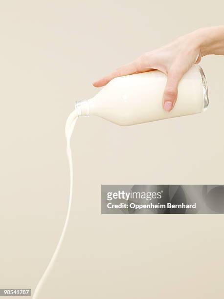 female hand pouring milk from container - milk bottle photos et images de collection