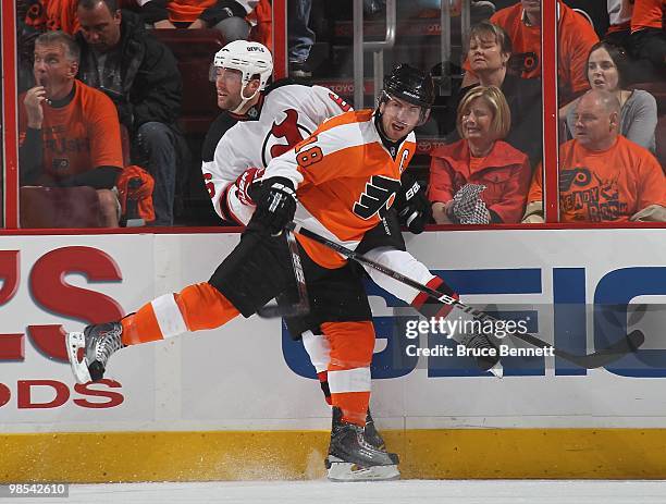 Mike Richards of the Philadelphia Flyers hits Andy Greene of the New Jersey Devils in Game Three of the Eastern Conference Quarterfinals during the...