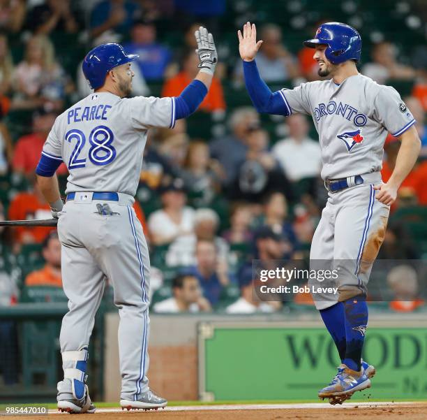 Randal Grichuk of the Toronto Blue Jays receives a high five from Steve Pearce after scoring on a double off the bat of Yangervis Solarte in the...