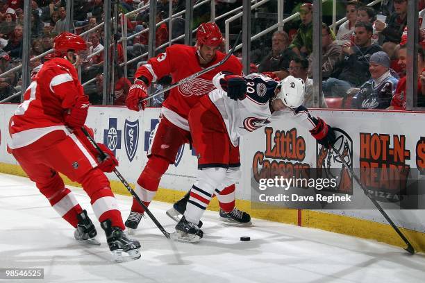 Greg Moore of the Columbus Blue Jackets battles for the puck with Andreas Lilja and Drew Miller of the Detroit Red Wings during an NHL game at Joe...