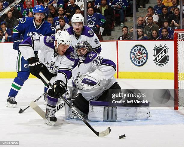 Drew Doughty of the Los Angeles and Daniel Sedin of the Vancouver Canucks look on as Rob Scuderi of the Los Angeles Kings clears a rebound from in...