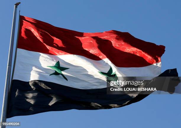 Picture taken on June 27, 2018 shows a Syrian national flag fluttering during the opening of a flower show at Tishreen Park in the capital Damascus.