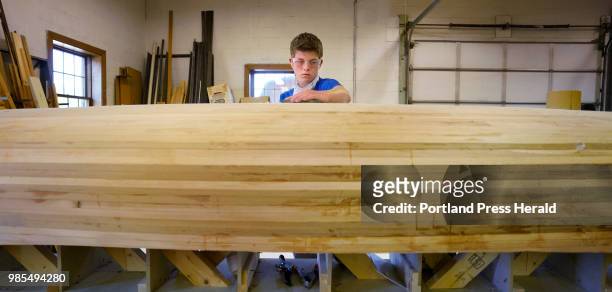 Shane Collins, a freshman in the Alternative Education program at Old Orchard Beach High School, sands the bottom of a 16-foot cedar strip canoe in a...