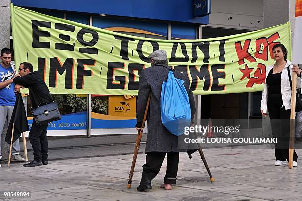 Homeless man looks at a banner reading 'IMF Go Home' held by leftist unionists in front of the finance ministry in Athens on April 19, 2010. Greece...