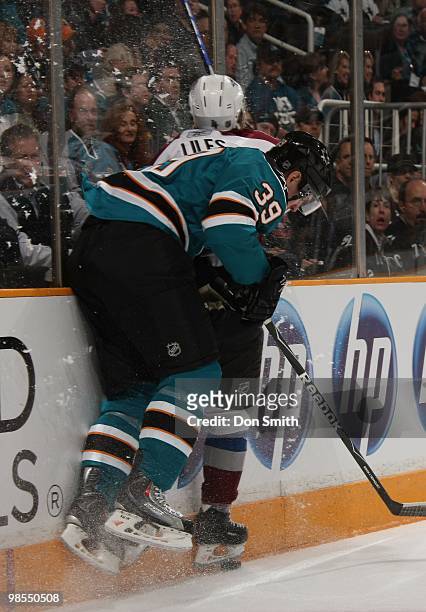 John-Michael Liles of the Colorado Avalanche gets checked from behind by Logan Couture of the San Jose Sharks in Game One of the Western Conference...