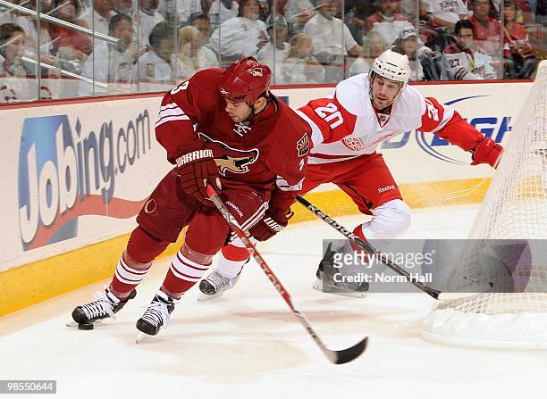 Keith Yandle of the Phoenix Coyotes keeps control of the puck with his skate while being chased by Drew Miller of the Detroit Red Wings in Game Two...