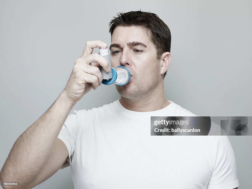 Person Using An Inhaler Man Using Asthma Inhaler And Aerochamber Spacer Photo - Getty Images