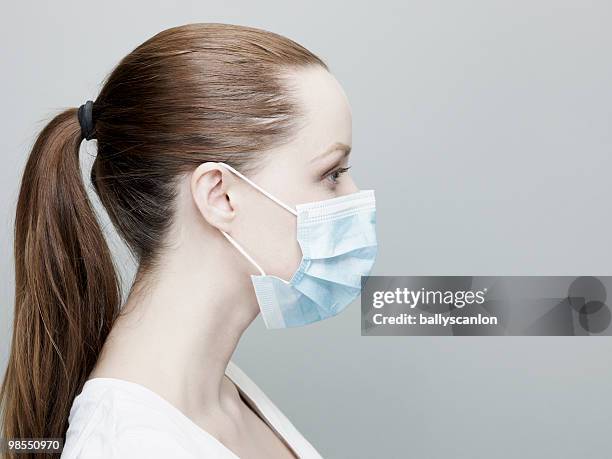 young woman wearing a surgical mask. - flu mask stock-fotos und bilder