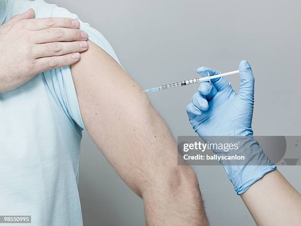 man receiving vaccination in arm. - arm needle stockfoto's en -beelden