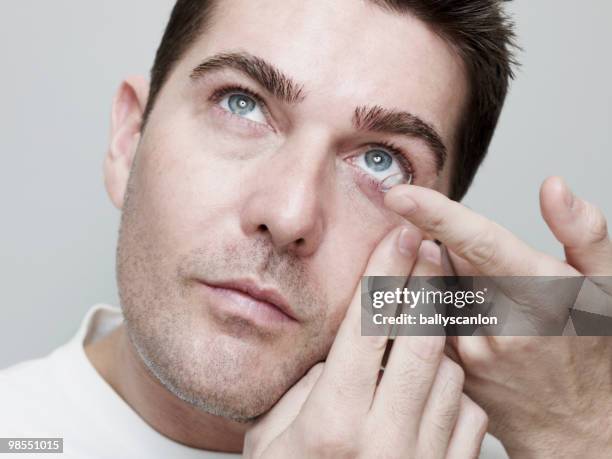 man inserting/guiding contact lenses. - inserting stock pictures, royalty-free photos & images