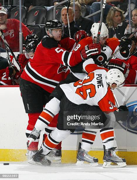 Colin White of the New Jersey Devils checks Mike Richards and Darroll Powe of the Philadelphia Flyers at the same time in Game Two of the Eastern...