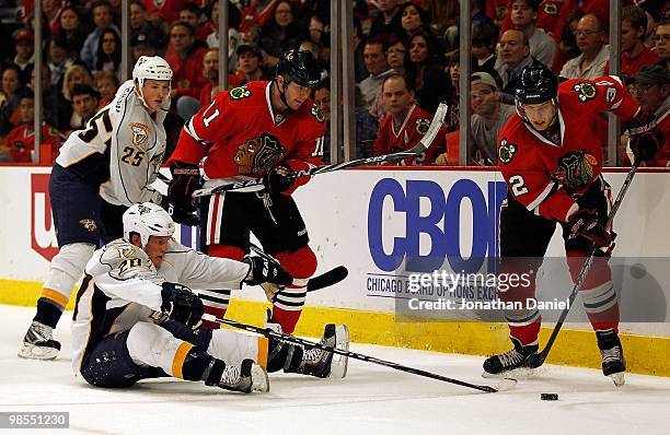 Ryan Suter of the Nashville Predators falls to the ice while battling for the puck with Kris Versteeg and John Madden of the Chicago Blackhawks while...