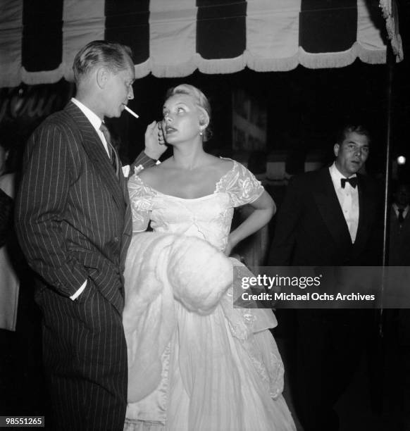 Actress Barbara Payton and fiancee actor Franchot Tone wait for their car outside the Mocambo nightclub on July 8, 1951 in Los Angeles, California.