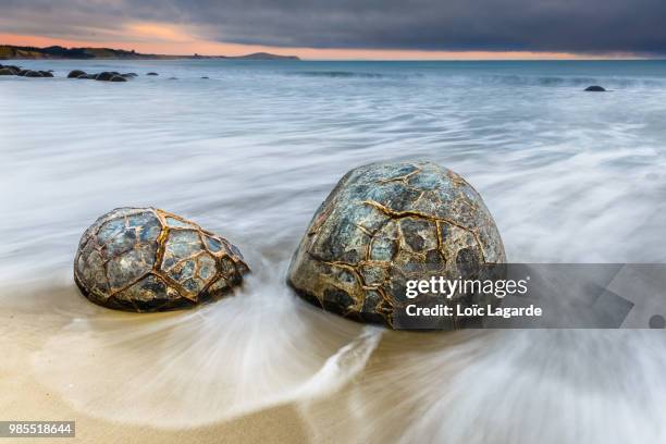 moeraki boulders on a cloudy sunrise - moeraki boulders ストックフォトと画像