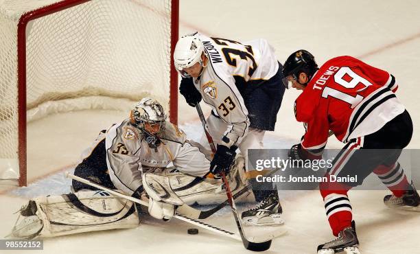 Jonathan Toews of the Chicago Blackhawks tries to slip the puck past Pekka Rinne and Colin Wilson of the Nashville Predators in Game One of the...