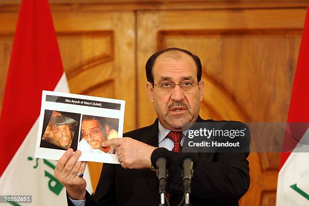 This handout image provided by the Iraqi Prime Minister office shows Iraq's Prime Minister Nouri al-Maliki holding photographs of a man identified by...