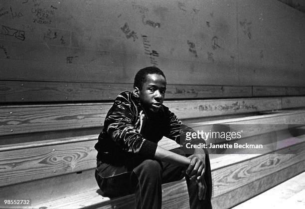 Portrait of American R&B singer Bobby Brown of the group New Edition as he sits on the bleachers in the gymnasium of Boston Technical High School ,...