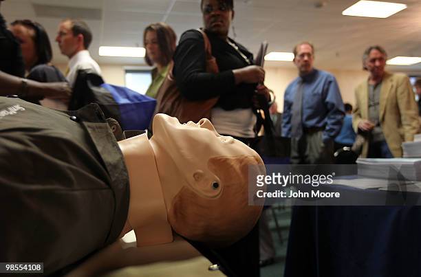 Job seekers file past a dummy at a booth for first responders courses at the "Job Hunters Boot Camp" on April 19, 2010 in Aurora, Colorado. Hundreds...