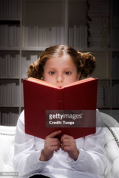 young girl reading book with spotlit on both - newpremiumuk stock pictures, royalty-free photos & images