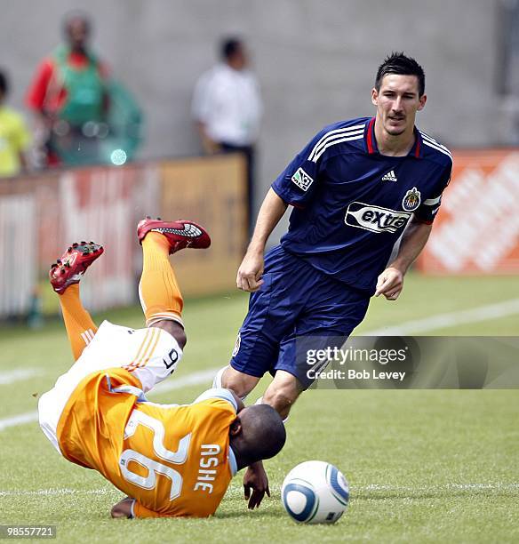 Corey Ashe of the Houston Dynamo takes a tumble as he is knocked down by Sacha Kljestan of Chivas USA at Robertson Stadium on April 17, 2010 in...