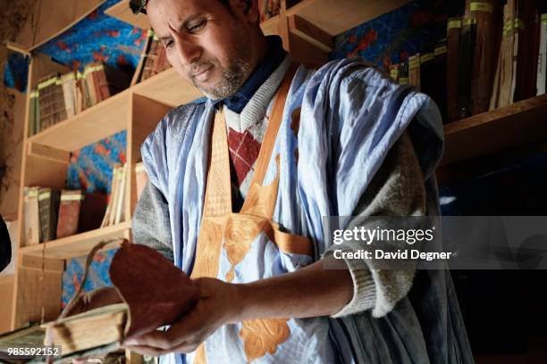 Mohamed Lemine Kettab looks at a book in the private library of the Kettab family of Ouadane, Mauritania. The city is famous for being a trading post...