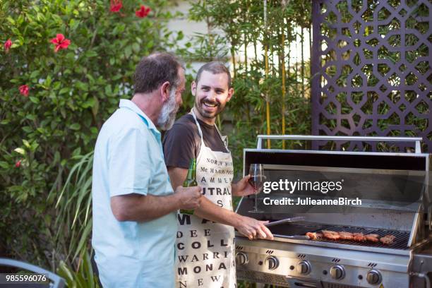 father and son grilling food on barbeque in yard - bbq australia stock pictures, royalty-free photos & images