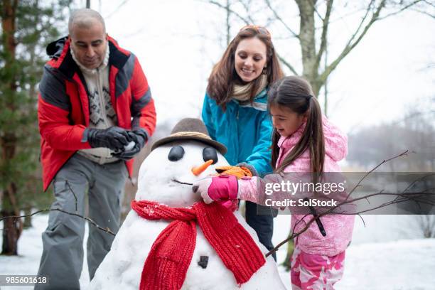 building a snowman with her family - making a snowman stock pictures, royalty-free photos & images