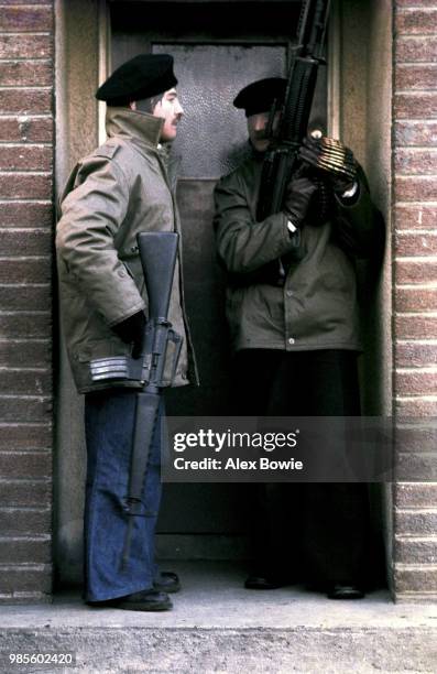 Masked IRA gunmen – one holding an Armalite rifle, the other an M-60 machine gun – crowd a doorway in the republican Creggan estate during a...