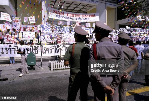 Police watch Thai university students protest against the huge Japanese trade surplus that exists with Thailand. One poster reads: 'Thai economy will...