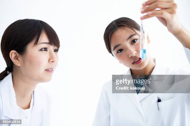 een vrouw observeren van de vloeistof in een reageerbuis. - petri schaal stockfoto's en -beelden