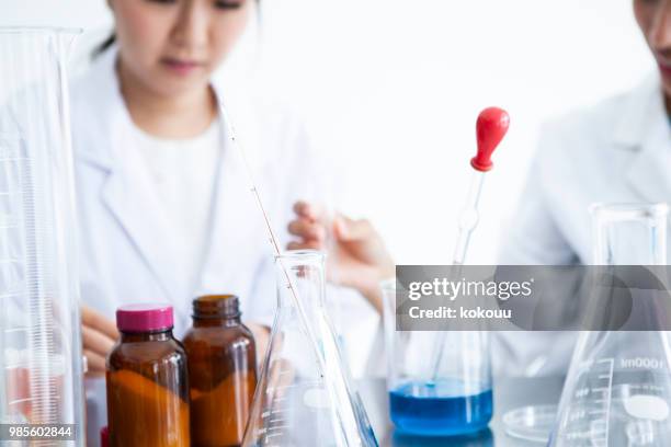 een vrouw observeren van de vloeistof in een reageerbuis. - petri schaal stockfoto's en -beelden