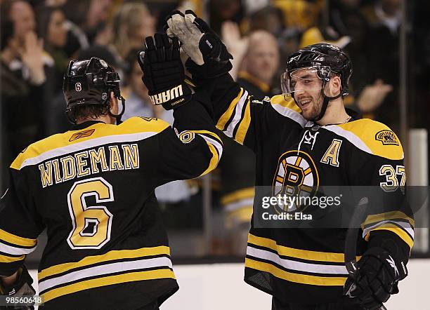 Patrice Bergeron and Dennis Wideman of the Boston Bruins celebrate the win over the Buffalo Sabres in Game Three of the Eastern Conference...