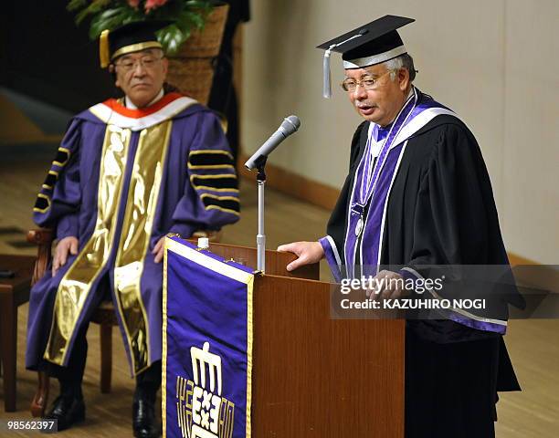 Malaysian Prime Minister Najib Razak delivers a speech while Hiromi Naya, president of Meiji University, looks on during a conferment ceremony of an...