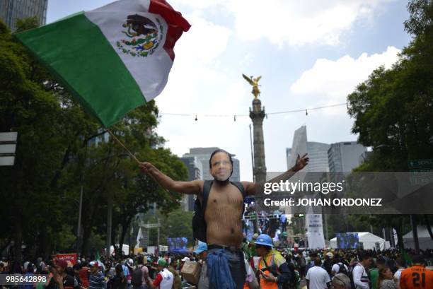 Football fan wearing a mask of Mexican former footballer Luis Alberto Alves -Zague- celebrates after Mexico passed through to the next round of the...