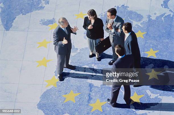group of business executives standing on world map with ec stars - international flags stock-fotos und bilder