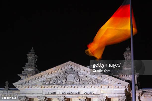 the famous inscription on the architrave on the west portal of the reichstag building in berlin: "dem deutschen volke" with german flag at night (berlin, germany) - architrave stock pictures, royalty-free photos & images