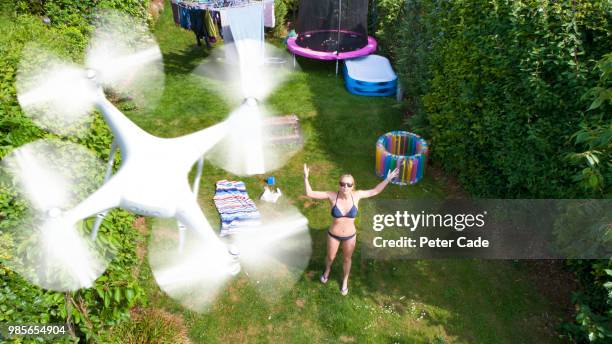 woman in garden sunbathing, being filmed by drone - bad neighbor foto e immagini stock