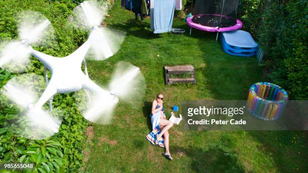 woman in garden sunbathing, being filmed by drone - peter law foto e immagini stock
