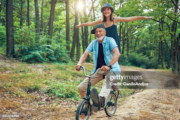 grootvader en zijn kleindochter plezier samen fietsen in de natuur - crazy old people stockfoto's en -beelden