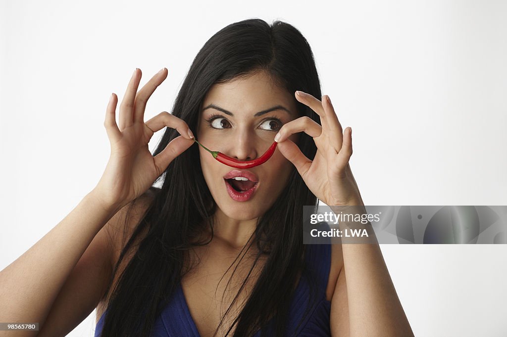 Woman Using Chili Pepper To Make Moustache