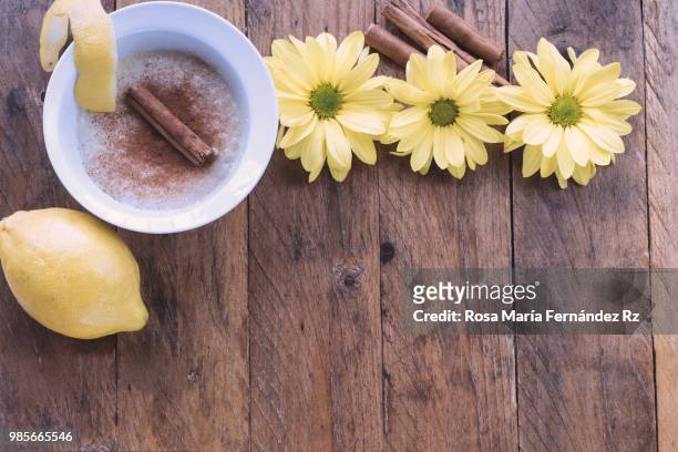 directly above of bowl of milk rice pudding sprinkle with cinnamon, cinnamon stick, lemon fruit and three daisies on rustic wooden background. copy space - rz stock pictures, royalty-free photos & images
