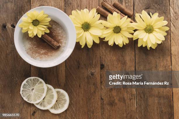 directly above of bowl of milk rice pudding sprinkle with cinnamon, cinnamon stickes, lemon slices and three daisies on rustic wooden background. copy space - rz stock pictures, royalty-free photos & images