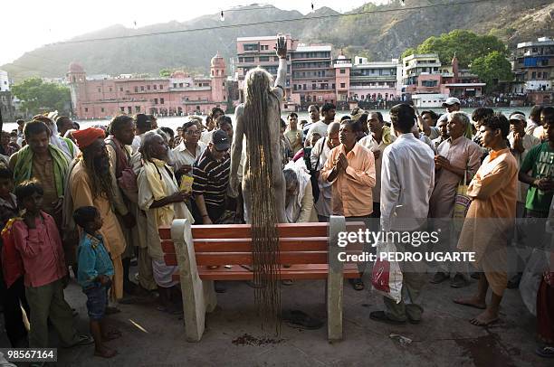 Hindu holi man stands on a bench on the banks of river Ganges during the Kumbh Mela festival on April 13, 2010 in Haridwar.The Kumbh Mela, world's...