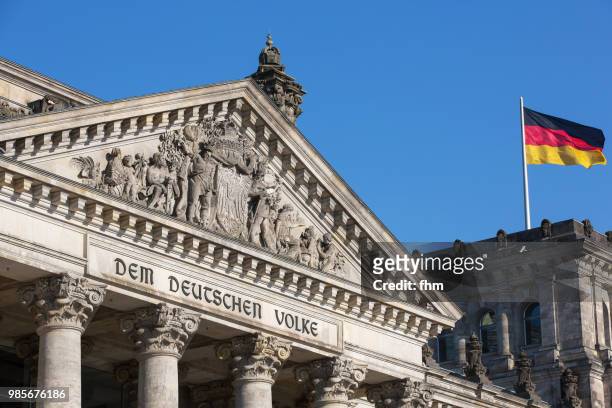 the famous inscription on the architrave on the west portal of the reichstag building in berlin: "dem deutschen volke" with german flag - architrave stock pictures, royalty-free photos & images