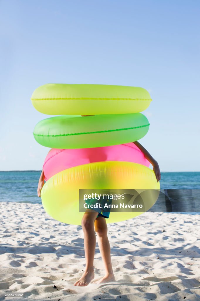Young boy on the beach wearing four inflatable rings