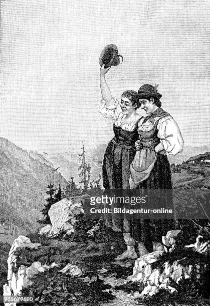 Greeting from the alpine pasture, two women in the Dirndl standing at a mountain path and looking into the valley, Bavaria, Germany, Gruss von der...