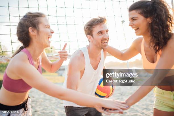 amigos juntando sus manos y jugar voleibol - campeón de torneo fotografías e imágenes de stock