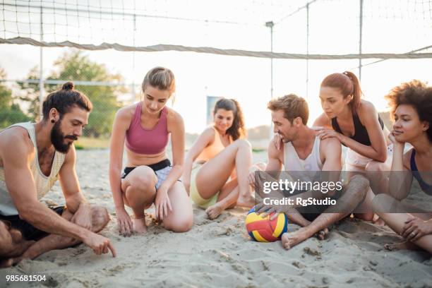 jogadores de voleibol sentado na praia - tournament champion - fotografias e filmes do acervo